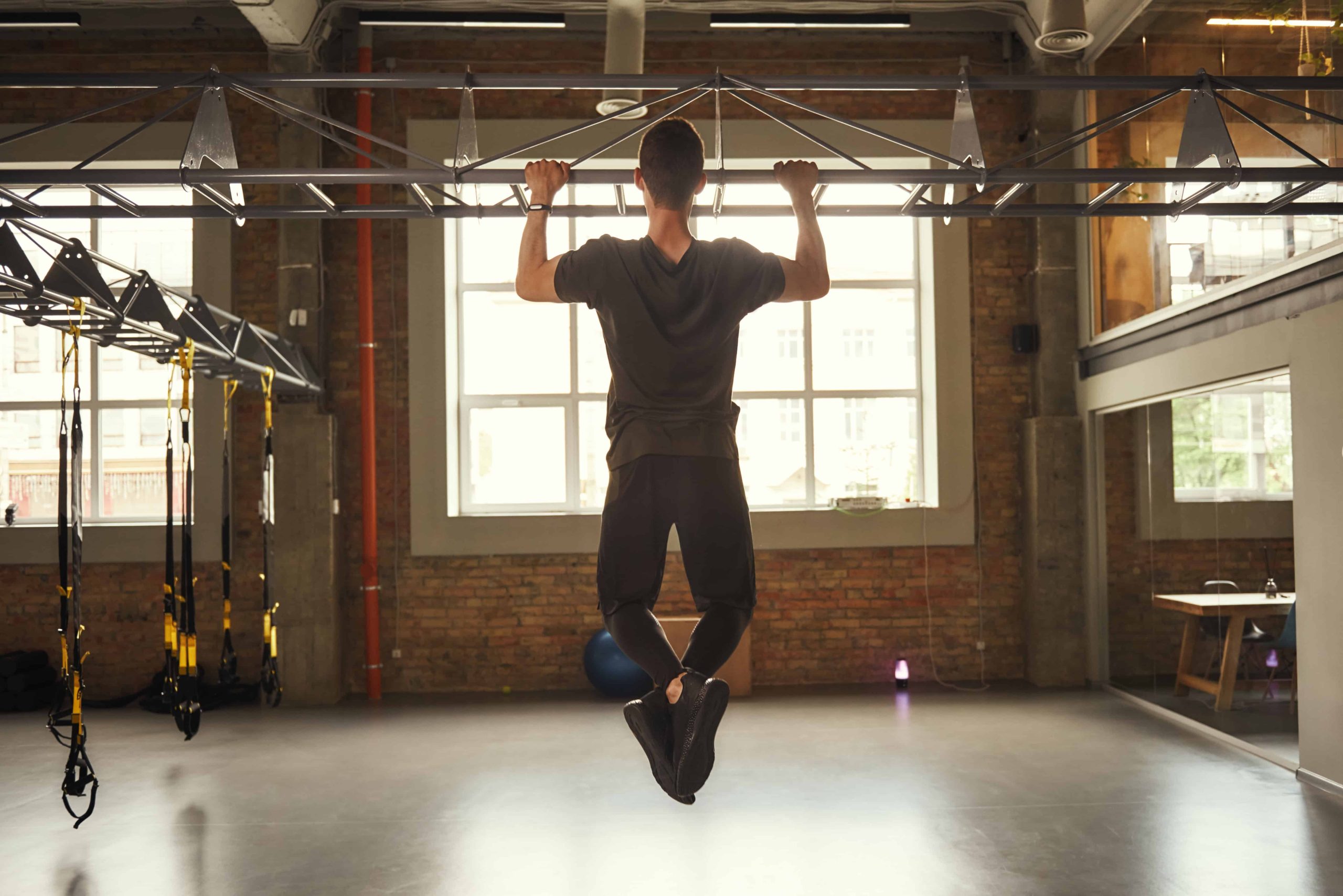 man doing a pull up in a gym
